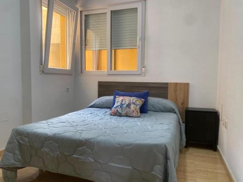 a bedroom with a bed with a blue comforter and two windows at Casa fina y pepe in Algar