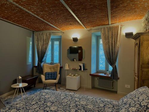 a bedroom with a bed and a chair and a tv at Le Relais du Bourg Chambres de charme Wellnes in Donnas