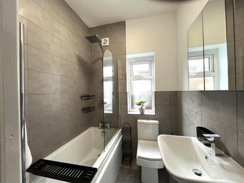 a bathroom with a tub and a toilet and a sink at Spacious home sleeps 8 Nr Etihad Coop Live & City in Manchester