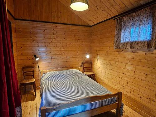 une chambre avec un lit dans une pièce en bois dans l'établissement Le Noisetier, à Mélisey