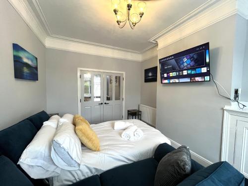 a bedroom with a large white bed with a flat screen tv at Spacious home sleeps 8 Nr Etihad Coop Live & City in Manchester