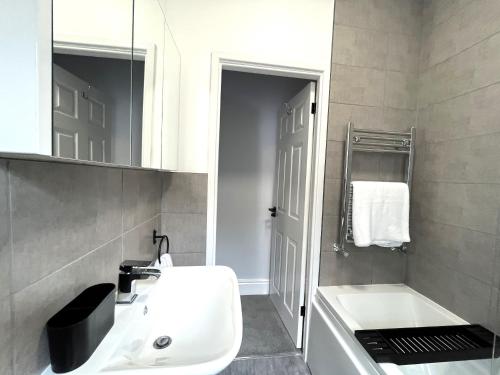 a bathroom with a sink and a tub and a mirror at Spacious home sleeps 8 Nr Etihad Coop Live & City in Manchester