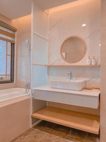a bathroom with a sink and a tub and a mirror at Tony Apartment -FLC Sea Tower Quy Nhon in Quy Nhon