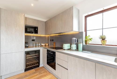 a kitchen with white cabinets and a large window at City View Spacious 2 bedroom Penthouse in London