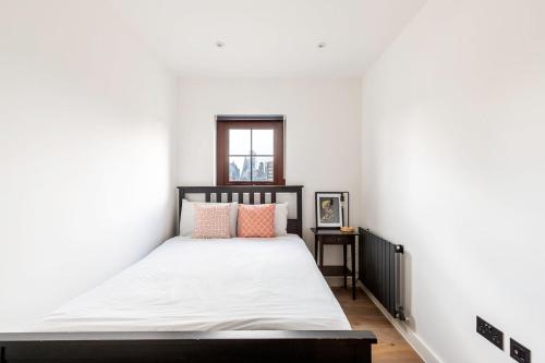a bedroom with a bed with white sheets and pink pillows at City View Spacious 2 bedroom Penthouse in London