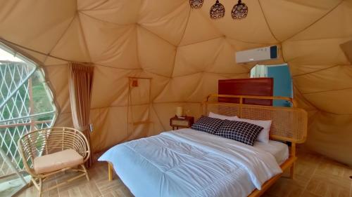 a bedroom in a tent with a bed and a chair at Kusumanagara Dome1 in Panjadakan