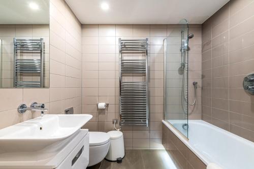 a bathroom with a sink and a tub and a toilet at Trendy Kings Cross Flat in London