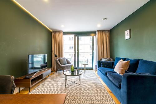 a living room with a blue couch and a tv at Trendy Kings Cross Flat in London