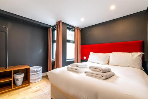 a bedroom with a large white bed with a red headboard at Trendy Kings Cross Flat in London