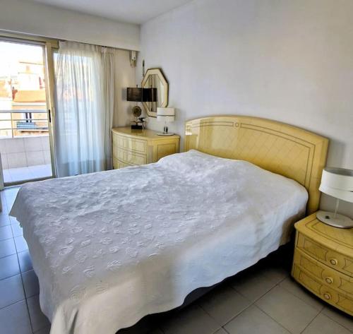 une chambre avec un grand lit blanc et une fenêtre dans l'établissement Cannes SEASIDE BEACHFRONT bord de mer, à Cannes
