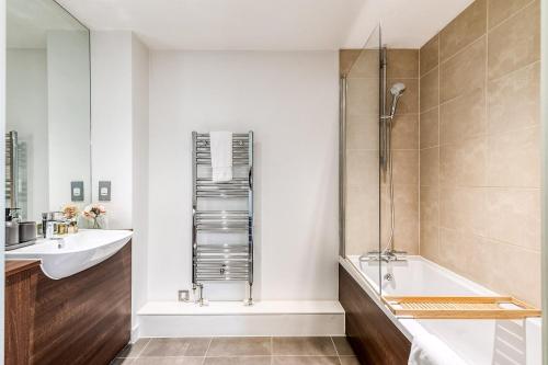 a bathroom with a tub and a sink and a bath tub at Canning Town Pied-à-Terre in London