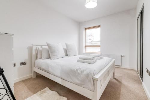 a white bedroom with a white bed with towels on it at Canning Town Pied-à-Terre in London