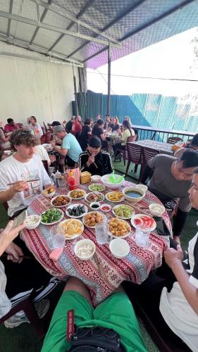 a group of people sitting around a table with food at Strawberry House , Tour & Motorbikes Rentel in Ha Giang