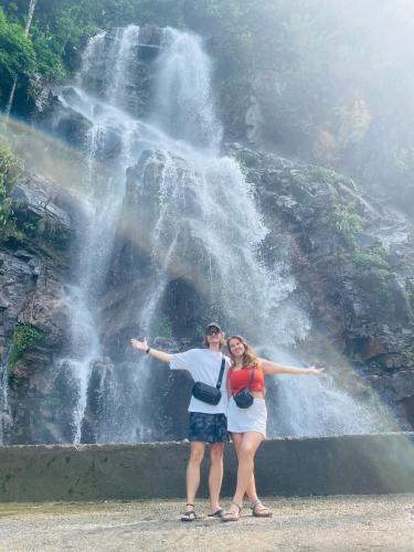 a man and woman standing in front of a waterfall at Strawberry House , Tour & Motorbikes Rentel in Ha Giang