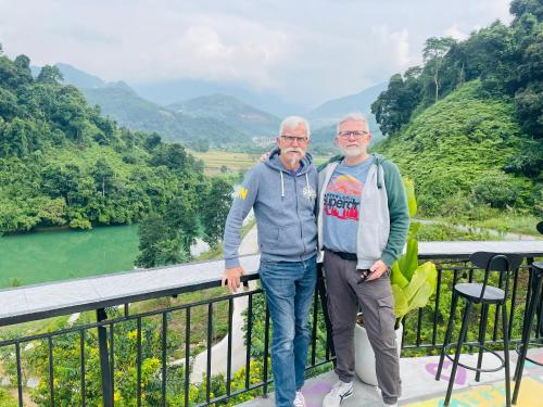 two older men standing on a balcony overlooking a river at Strawberry House , Tour & Motorbikes Rentel in Ha Giang