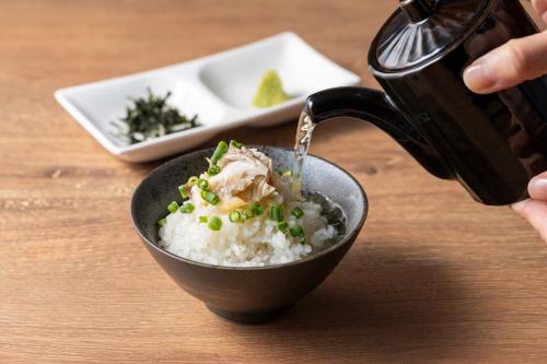 a person pouring food into a bowl of rice at Hotel JAL City Haneda Tokyo West Wing in Tokyo