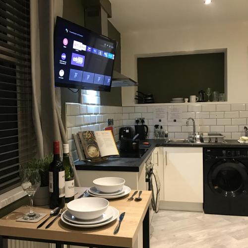 a kitchen with a table with plates and a tv at Contemporary 1 bed studio for comfy stay in Wigan in Wigan