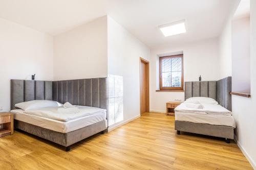 two beds in a room with wooden floors and white walls at Penzion Mountain in Čeladná