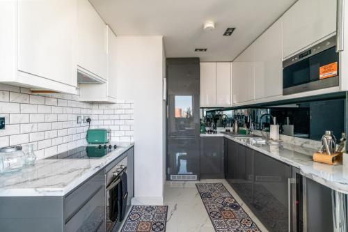 a large kitchen with white cabinets and black appliances at Canary Wharf Retreat with Free Secure Parking in London