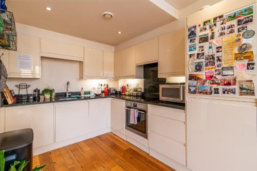 a white kitchen with white cabinets and appliances at Bright & Spacious Battersea Flat in London