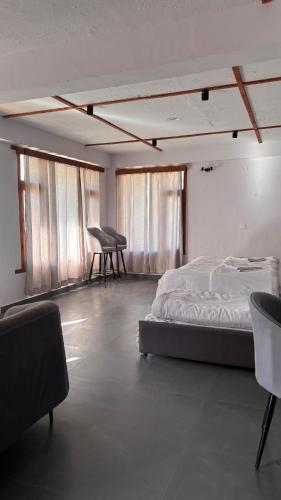 a bedroom with a bed and a desk and windows at Peppy Nomads Luxuria in Jibhi