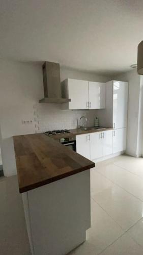 une cuisine avec des armoires blanches et un comptoir en bois dans l'établissement Maison 4 chambres avec jardin, à Châlette-sur-Loing