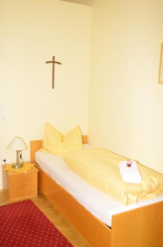 a bedroom with a bed with a cross on the wall at Gästehaus im Priesterseminar Salzburg in Salzburg