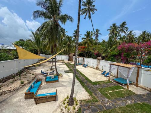 a resort with a hammock and chairs and palm trees at Mambo Cabana in Pwani Mchangani
