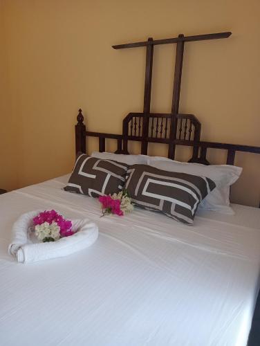 Una cama con dos toallas y flores. en Watamu tamu, en Watamu
