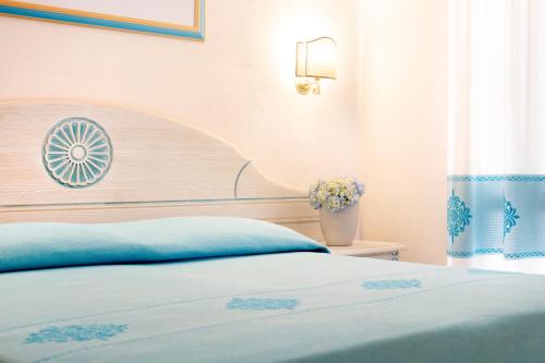 a bedroom with a bed and a vase of flowers at HOTIDAY Room Collection - Baja Sardinia in Baja Sardinia