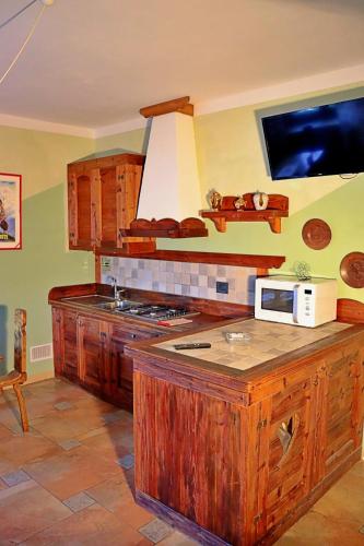 a kitchen with wooden cabinets and a microwave on a counter at Chèvres à Cheval - Apartment in Aosta