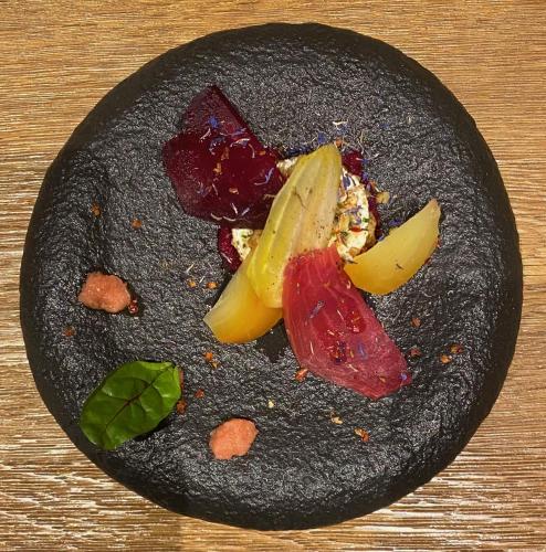 a black plate of food with vegetables on it at Lifestyle Rooms & Suites by Beau-Séjour in Champéry