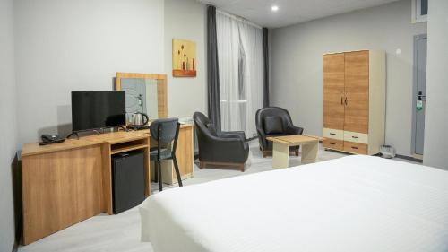 a bedroom with a bed and a desk with a television at Altınova Hotel Sakarya in Serdivan