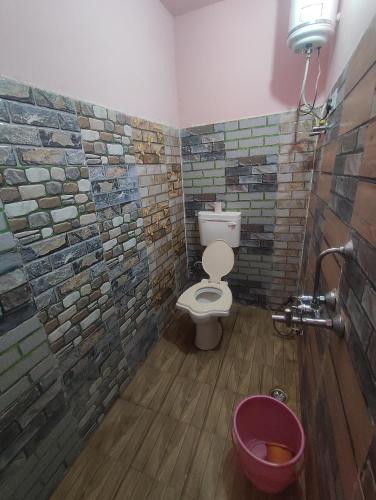 a bathroom with a toilet and a tile wall at Hotel Chacha's garden with restaurant pushkar in Pushkar