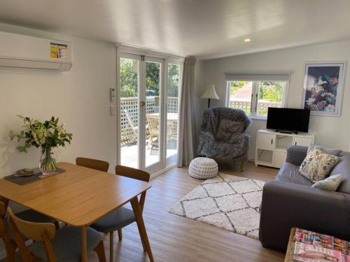 a living room with a table and a couch at Manuka Cottage Oneroa in Waiheke Island