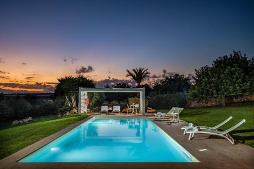 a swimming pool with two lawn chairs and a table at VILLA RAMUNNA 6, Emma Villas in Rosolini