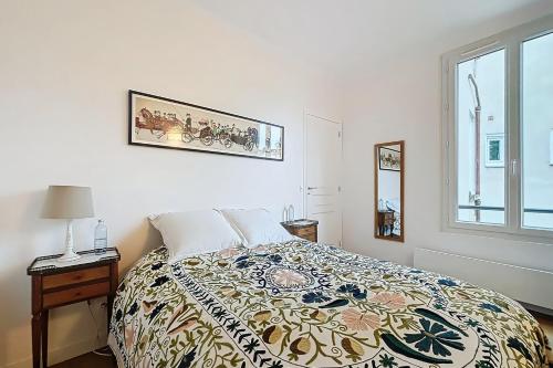 - une chambre avec un lit doté d'une couverture colorée et d'une fenêtre dans l'établissement A cosy haven in Versailles charm and comfort, à Versailles