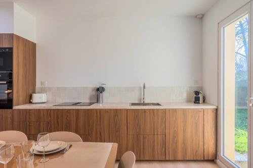 une cuisine avec des armoires en bois et une table avec des chaises dans l'établissement Maison 3 chambres et 2 salle de bain avec jardin, à Tourcoing