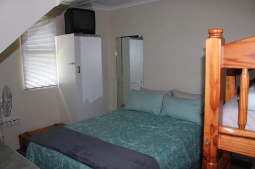 a bedroom with a bed and a tv on the wall at Holiday Villa Diaz Beach Mossel Bay in Mossel Bay