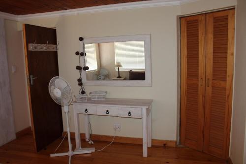 a room with a table with a mirror and a fan at Holiday Villa Diaz Beach Mossel Bay in Mossel Bay