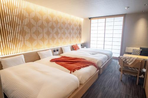 a room with three beds and a table and a window at ORI Kyoto in Kyoto
