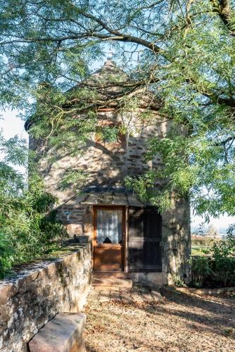 un vieux bâtiment en pierre avec une porte sous un arbre dans l'établissement La Petite Tour du Château de Salornay, à Hurigny
