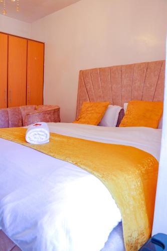 a bedroom with two beds with orange pillows at Signature Mall Rio Vista Furnished Studios Nairobi in Marimbeti