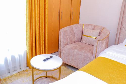 a bedroom with a chair and a table and a bed at Signature Mall Rio Vista Furnished Studios Nairobi in Marimbeti