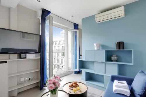 - un salon bleu avec un canapé et une télévision dans l'établissement Résidence Saint-Lazare, à Paris