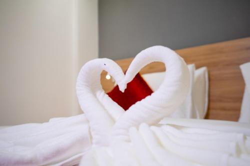 two white swans making a heart on a bed at AJ Palace in Alleppey