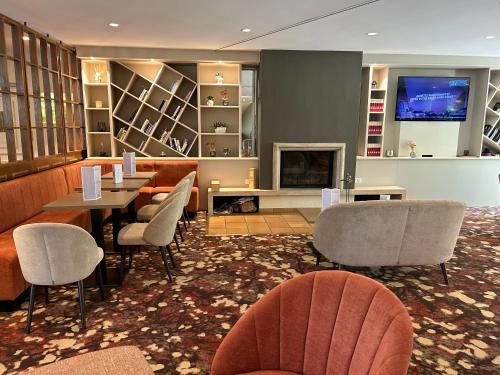 a restaurant with chairs and a table and a fireplace at Hôtel du Parc in Hardelot-Plage