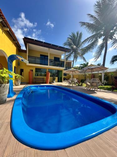 a large blue swimming pool in front of a house at Pousada Gamela do Maragogi in Maragogi