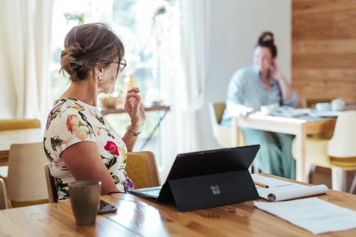 a woman sitting at a table with a laptop at Hotel Het Buskruid in Lummen
