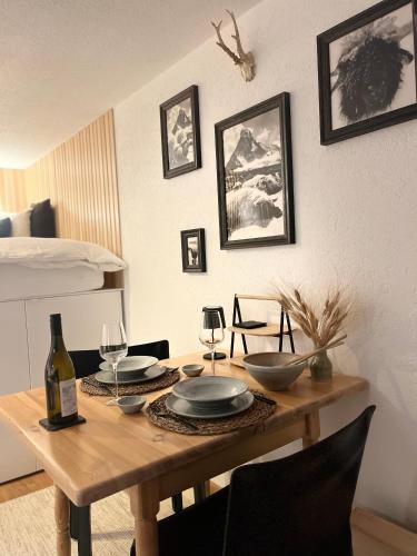 a wooden table with plates and wine glasses on it at Sonnmatten Boutique Hotel & Apartments Zermatt in Zermatt